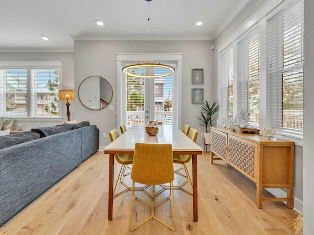 dining space with light wood-style floors, a healthy amount of sunlight, and crown molding