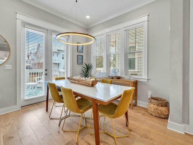 dining space with a healthy amount of sunlight, light wood-style flooring, baseboards, and ornamental molding