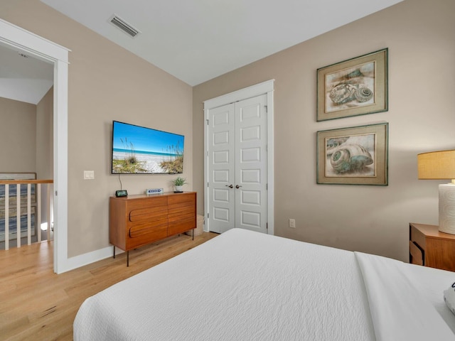 bedroom with baseboards, a closet, visible vents, and wood finished floors