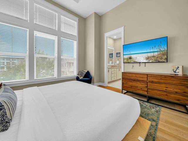 bedroom with light wood finished floors and ensuite bathroom