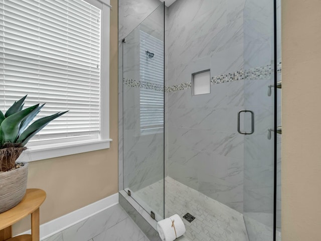 full bathroom with marble finish floor, a shower stall, and baseboards