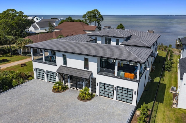 view of front of house featuring a garage, a balcony, and a water view