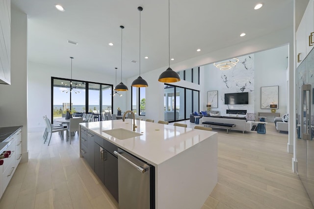 kitchen with pendant lighting, sink, a center island with sink, and white cabinets