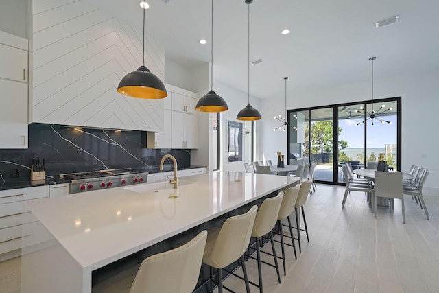 kitchen with pendant lighting, sink, a large island, a notable chandelier, and white cabinets