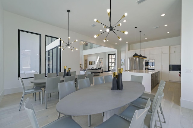 dining space with a notable chandelier, sink, and light wood-type flooring