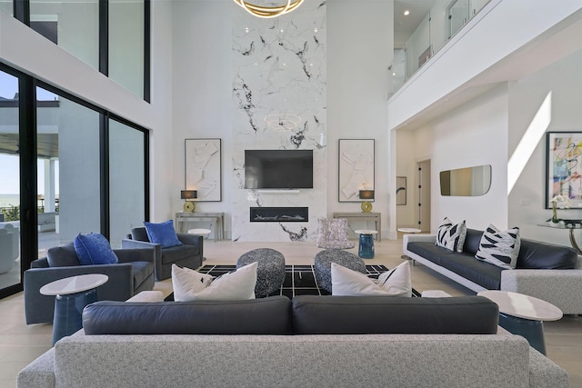 living room with a towering ceiling, a premium fireplace, and light hardwood / wood-style floors