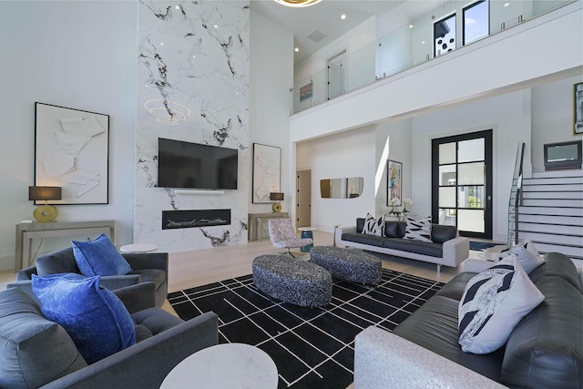 living room featuring a premium fireplace, dark hardwood / wood-style flooring, and a high ceiling