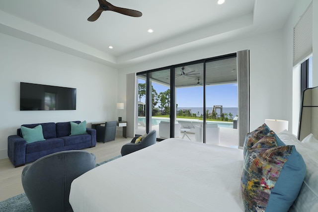 bedroom featuring ceiling fan, a tray ceiling, access to exterior, and light wood-type flooring