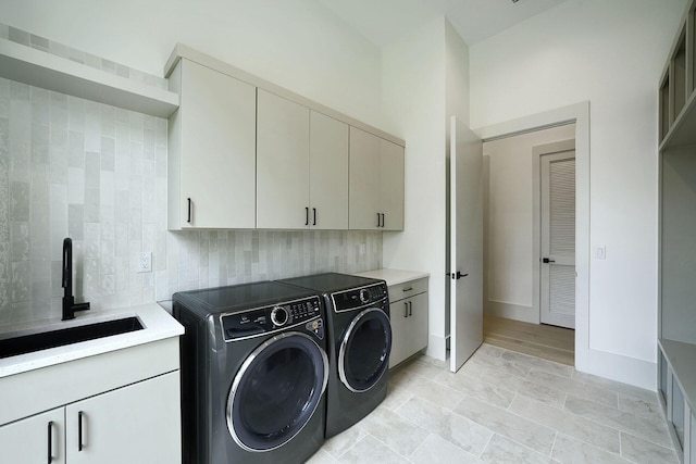 laundry room with cabinets, washer and dryer, and sink