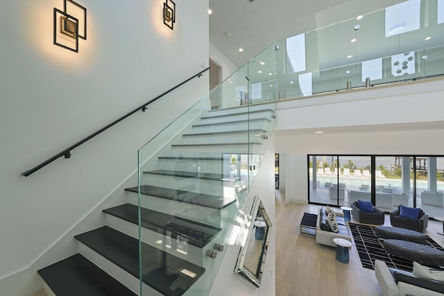 stairs featuring a towering ceiling and hardwood / wood-style floors