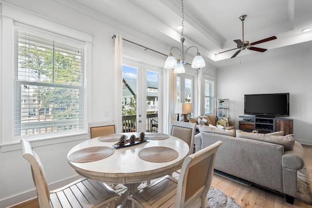 dining space featuring ceiling fan with notable chandelier, light hardwood / wood-style floors, and a raised ceiling