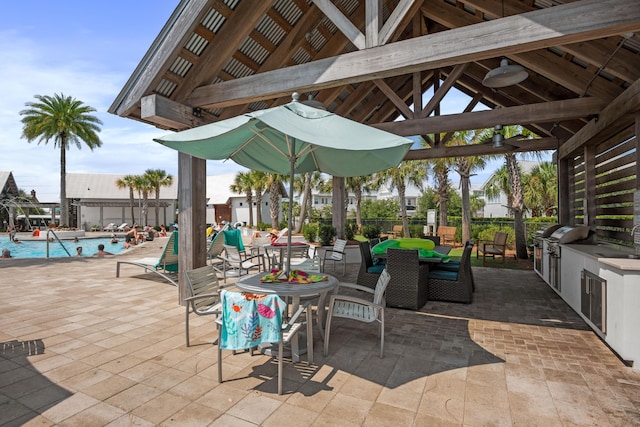 view of patio / terrace with a gazebo, an outdoor kitchen, a grill, and a community pool