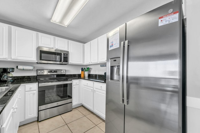 kitchen with stainless steel appliances, light tile patterned floors, and white cabinets