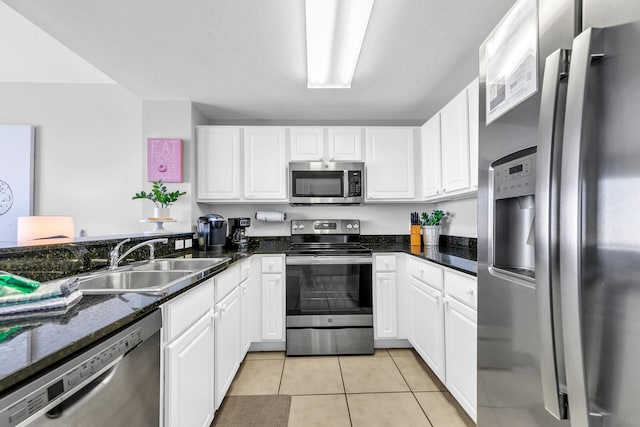 kitchen with sink, light tile patterned floors, dark stone countertops, stainless steel appliances, and white cabinets