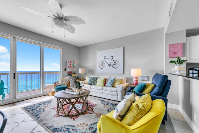 tiled living room featuring ceiling fan and a water view