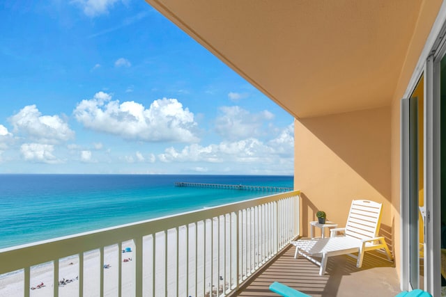 balcony with a water view and a view of the beach