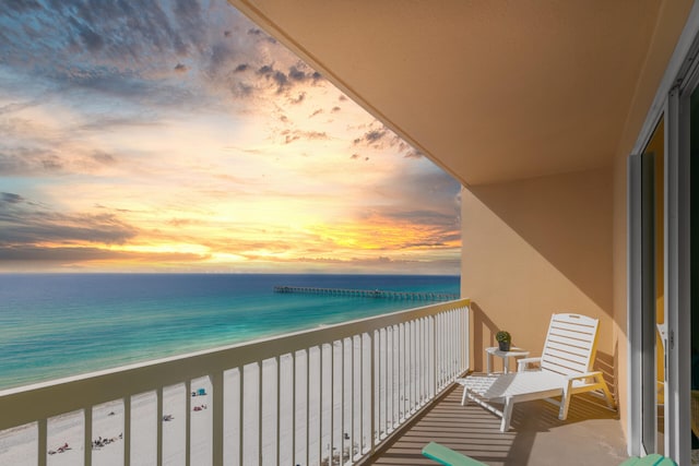 balcony at dusk with a water view and a beach view