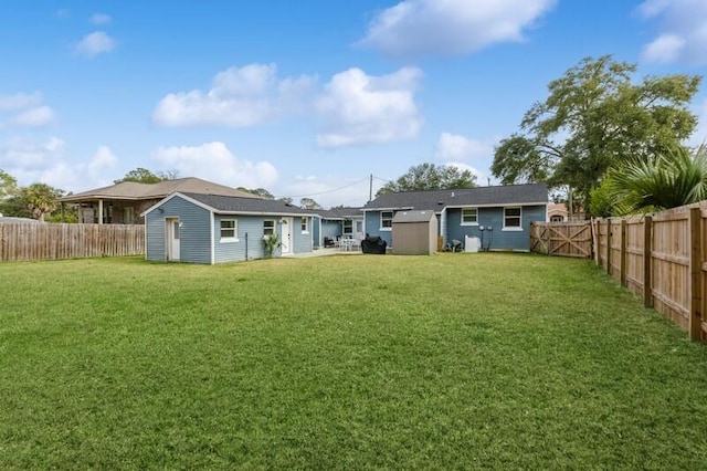 back of house with a yard, a fenced backyard, an outdoor structure, and a storage unit