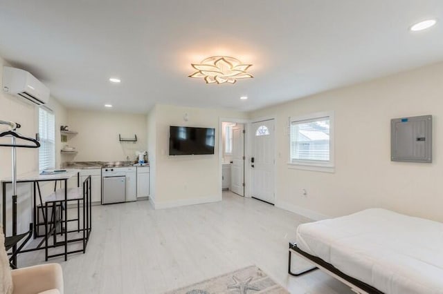 bedroom featuring light wood-style floors, electric panel, baseboards, and a wall mounted air conditioner