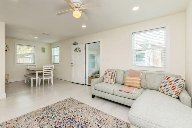 living area with baseboards, a ceiling fan, light wood-style flooring, and recessed lighting