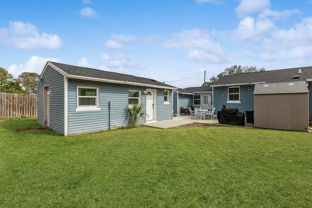 rear view of property with an outbuilding, a patio, fence, a lawn, and a storage unit