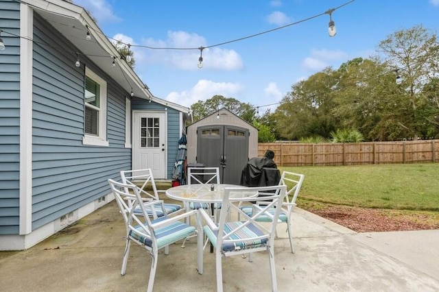 view of patio with outdoor dining space, an outdoor structure, fence, and a storage unit