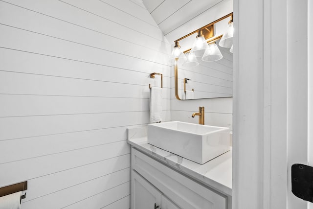 bathroom with vanity, lofted ceiling, and wood walls