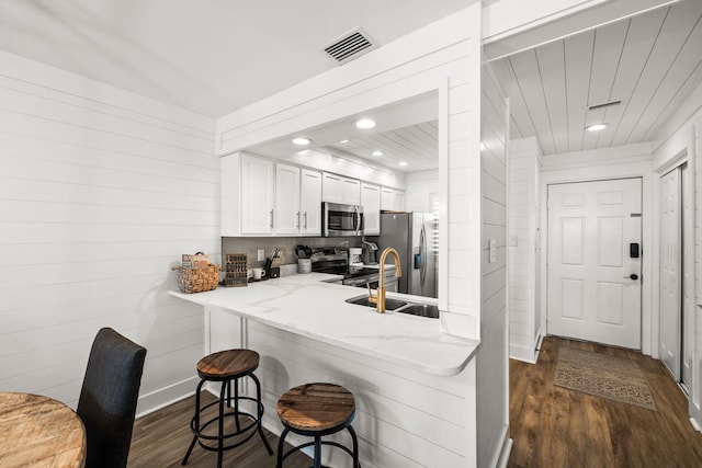 kitchen with a breakfast bar, sink, dark hardwood / wood-style floors, kitchen peninsula, and stainless steel appliances