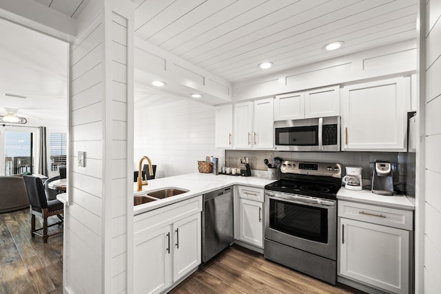 kitchen with sink, appliances with stainless steel finishes, backsplash, dark hardwood / wood-style floors, and white cabinets