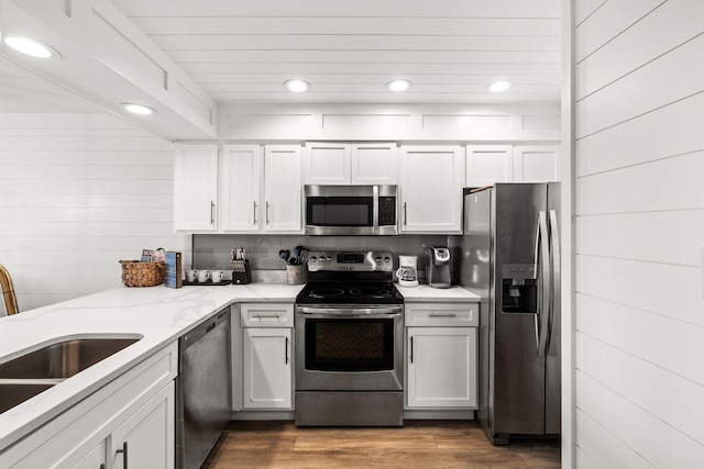 kitchen with light stone counters, appliances with stainless steel finishes, light hardwood / wood-style flooring, and white cabinets