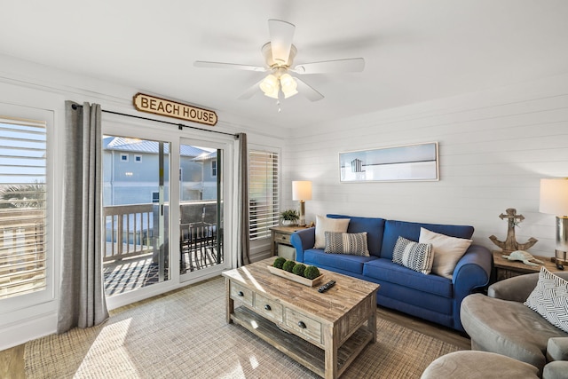 living room with a wealth of natural light, ceiling fan, and a water view