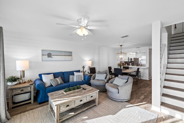 living room featuring ceiling fan with notable chandelier and hardwood / wood-style floors