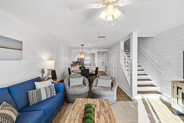 living room featuring hardwood / wood-style flooring, ceiling fan, and wooden walls