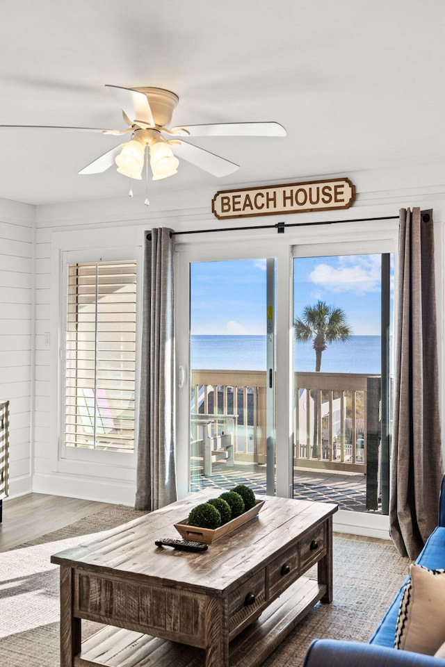 living room with hardwood / wood-style floors, ceiling fan, and a water view