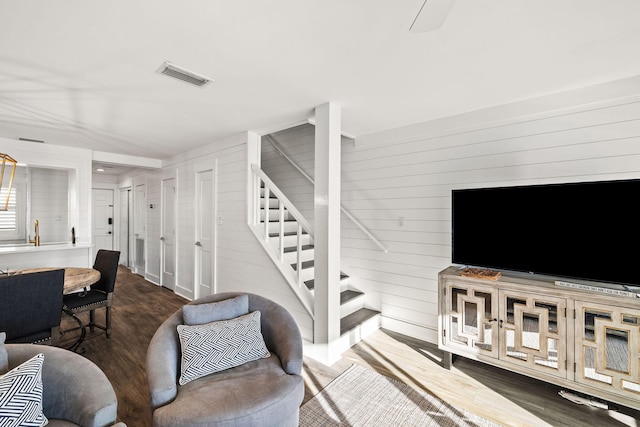 living room featuring dark wood-type flooring and wood walls