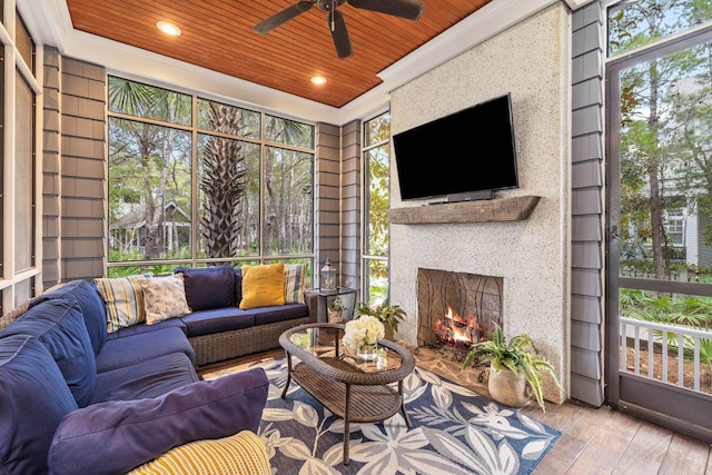 sunroom featuring wooden ceiling, ceiling fan, and a large fireplace