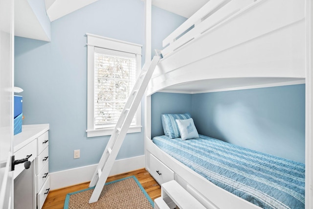 bedroom featuring light wood-type flooring, baseboards, and vaulted ceiling