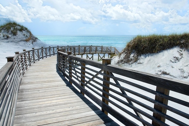 view of dock featuring a water view and a beach view