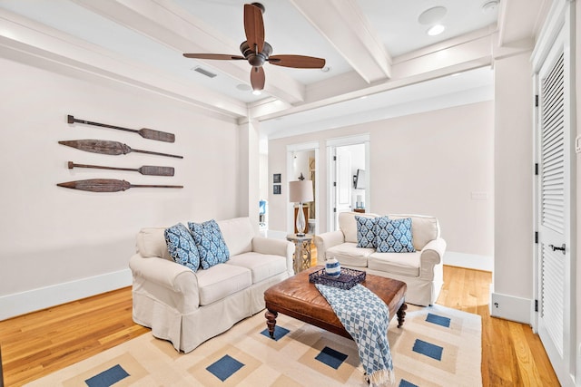 living room featuring visible vents, light wood-style flooring, a ceiling fan, beamed ceiling, and baseboards