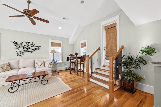 living room with baseboards, visible vents, lofted ceiling, wood finished floors, and stairs