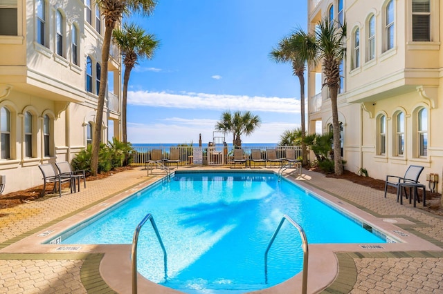 view of swimming pool featuring a patio and a water view