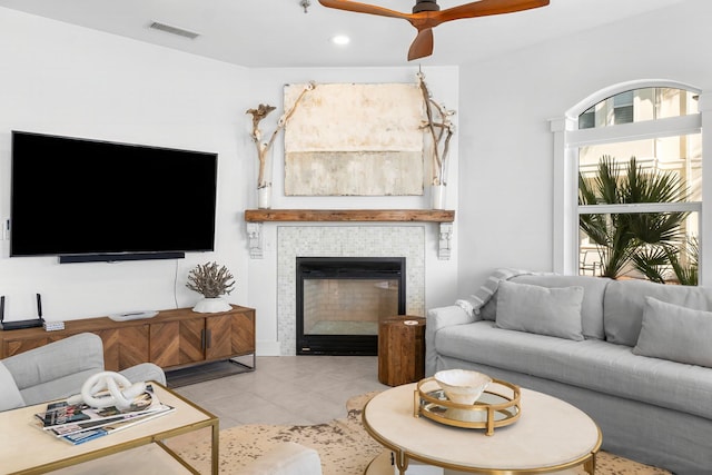 tiled living room featuring a tiled fireplace and ceiling fan