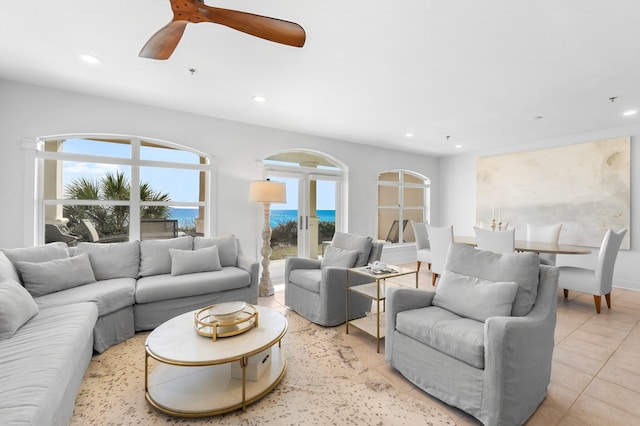 living room with a water view, ceiling fan, french doors, and light tile patterned floors