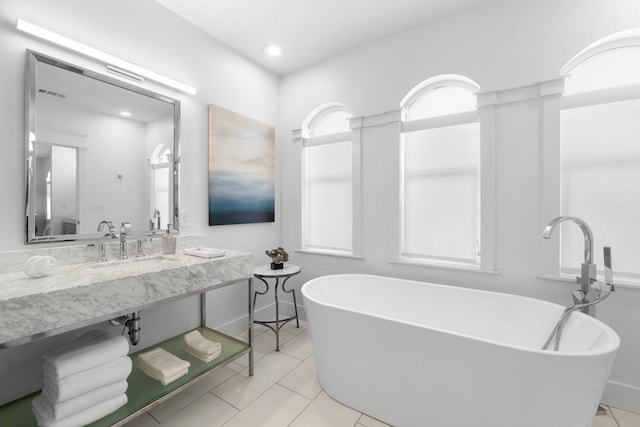 bathroom with tile patterned floors and a bath