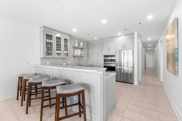 kitchen with sink, backsplash, appliances with stainless steel finishes, kitchen peninsula, and white cabinets