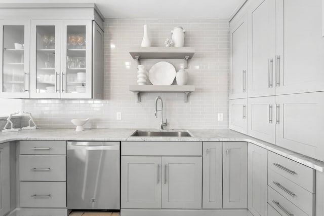 kitchen featuring light stone counters, sink, tasteful backsplash, and dishwasher