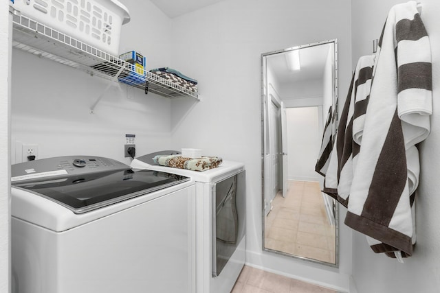 clothes washing area featuring light tile patterned floors and washing machine and clothes dryer