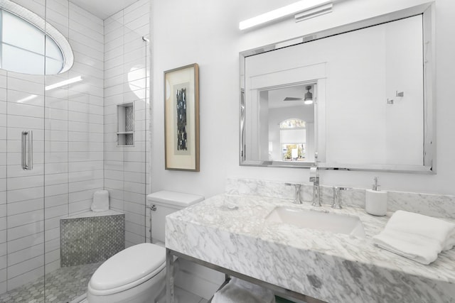 bathroom with walk in shower, ceiling fan, vanity, and toilet