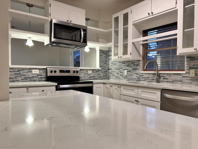 kitchen with tasteful backsplash, white cabinetry, sink, stainless steel appliances, and light stone countertops