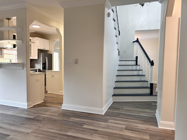 stairs with hardwood / wood-style flooring and ornamental molding